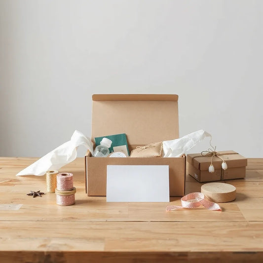 Open gift box on a wooden table with assorted items, ribbon, and blank card for a custom bundle